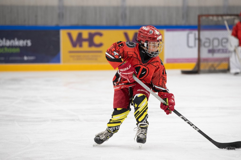 Junger Spieler beim Schusstraining auf dem Eis