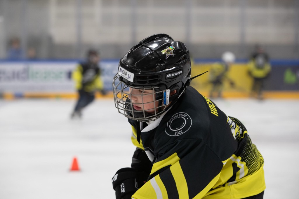 Junger Spieler im Hockey-Staff-Trikot beim Skating-Training auf dem Eis