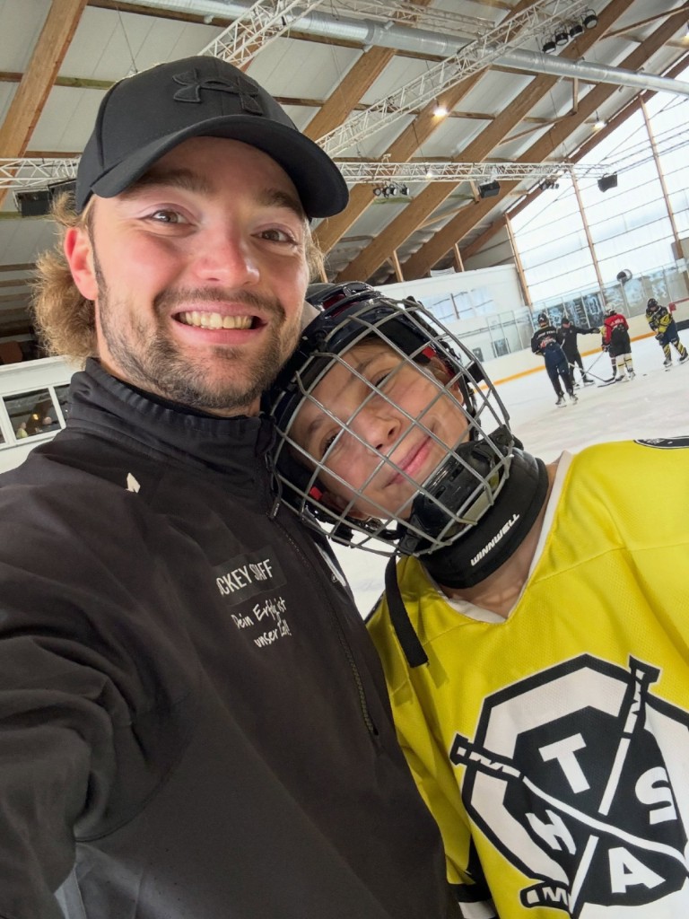 Trainer Anton Tsipan mit einem jungen Spieler auf dem Eis im Hockey-Staff-Trikot